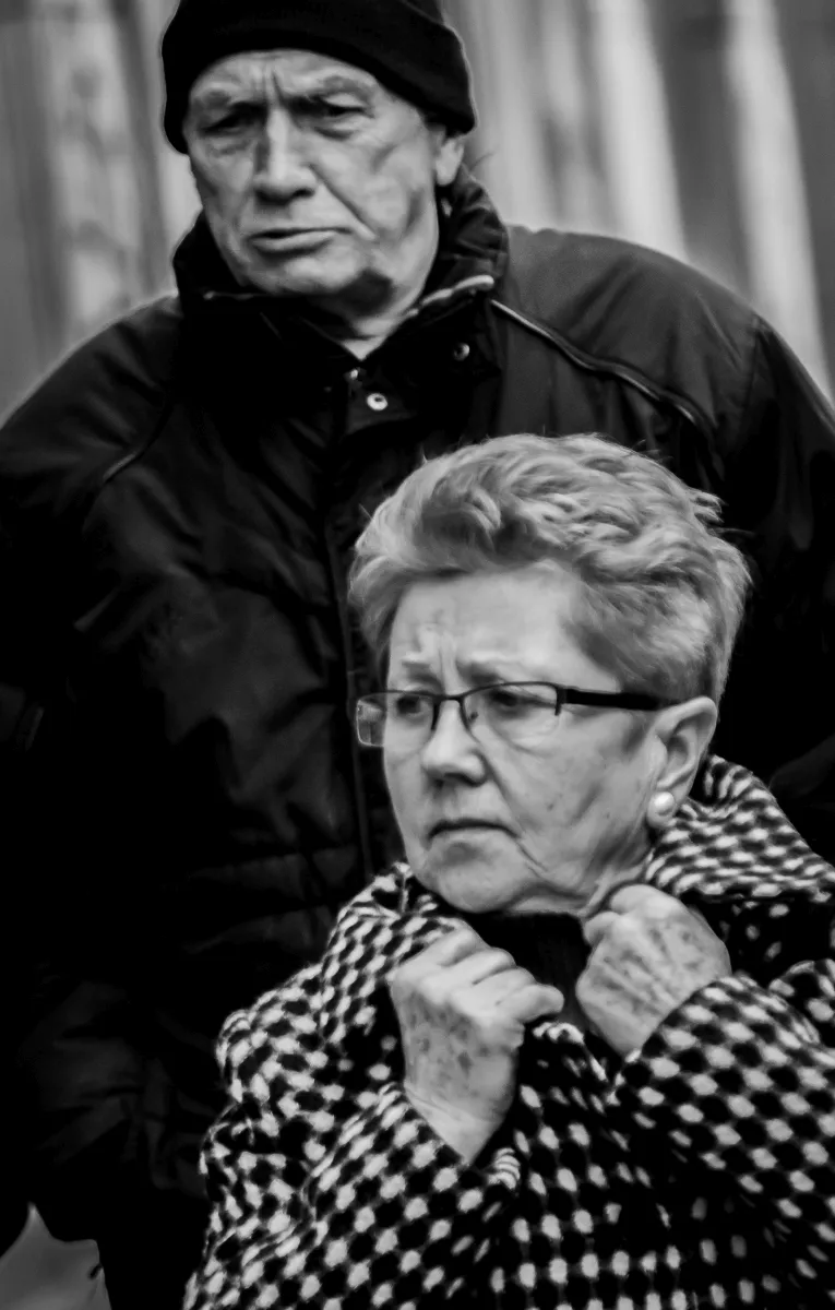 Close-up portraits of an older man and woman in a crowd
